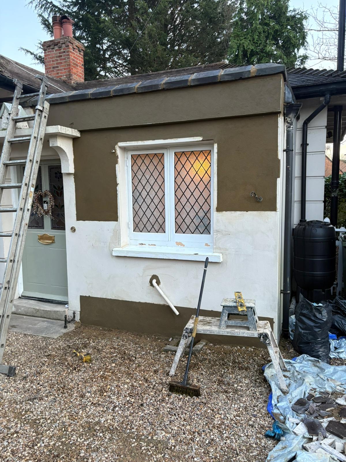 Render repairs in progress on a bungalow wall