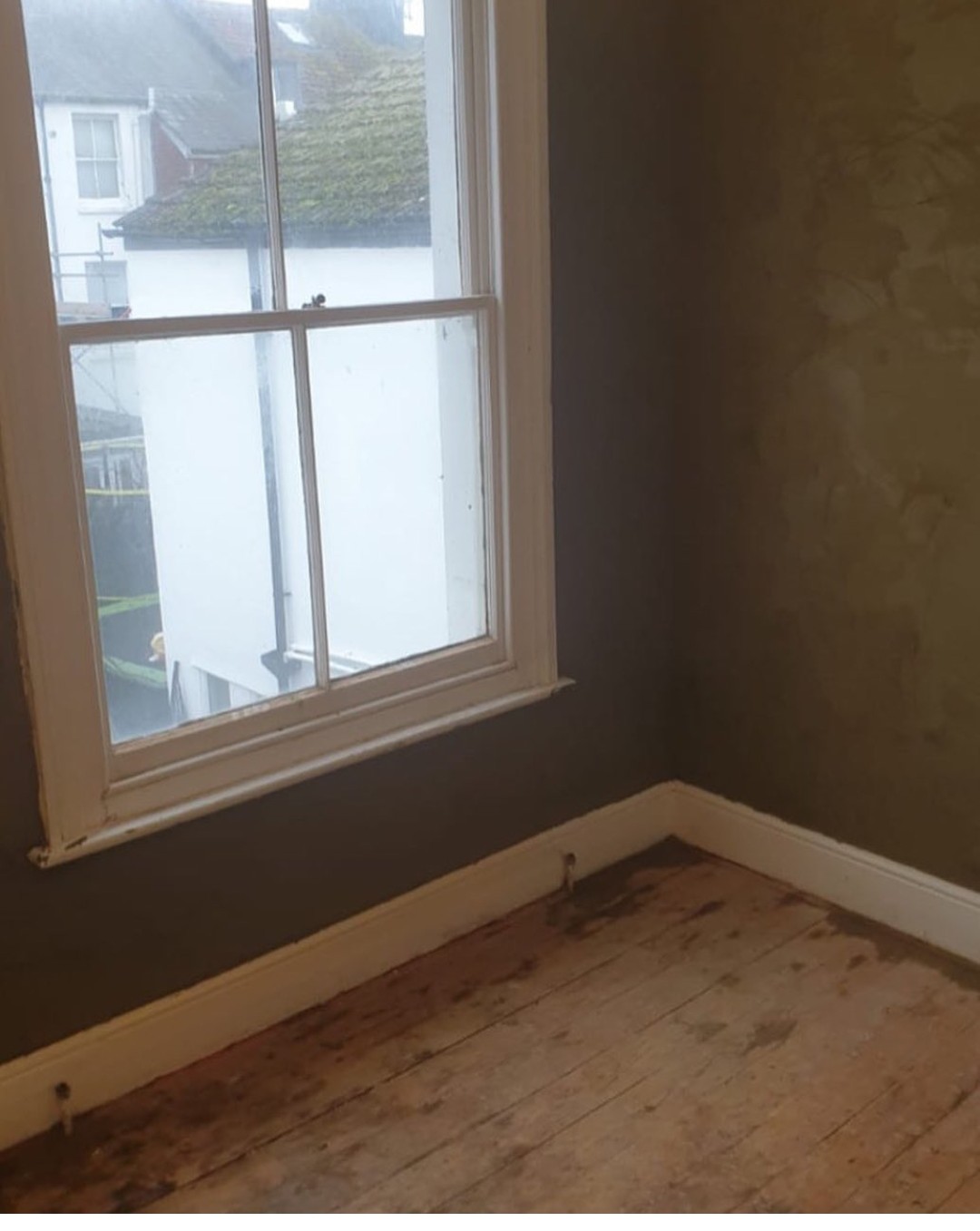 A freshly plastered room corner beside a sash window